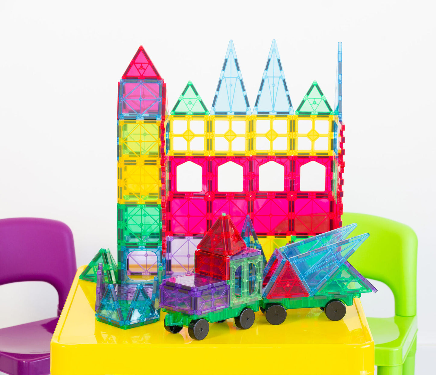 Colorful magnetic building blocks on a yellow table with chairs in the background
