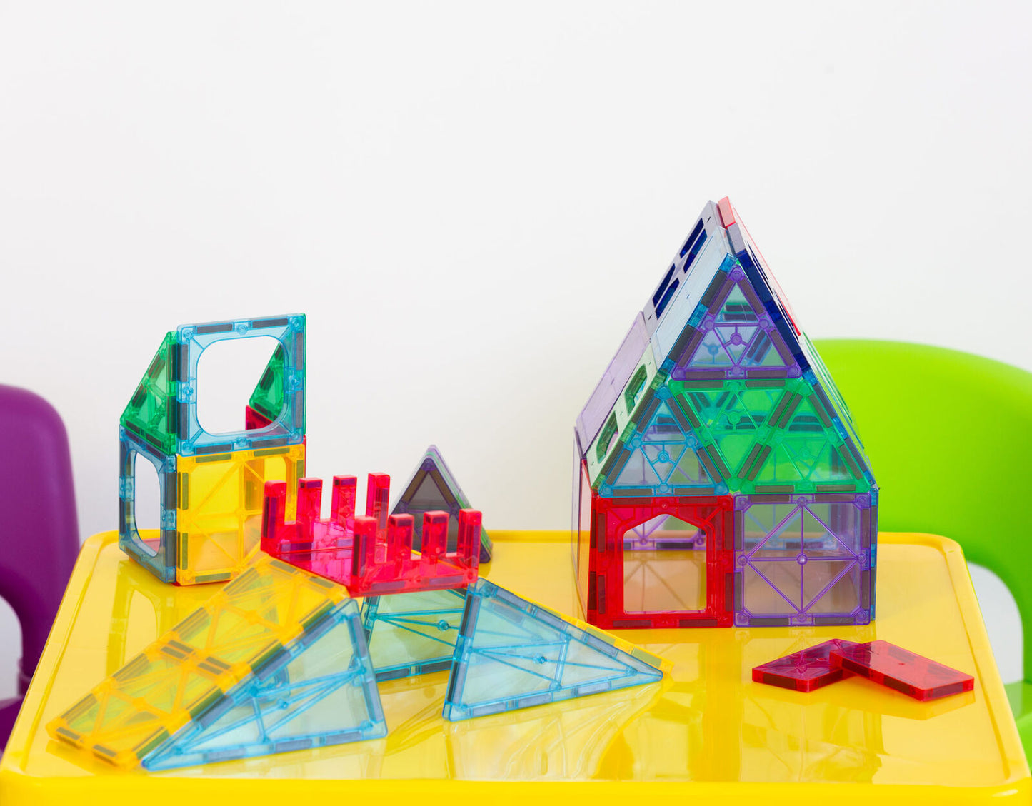 Colorful magnetic building blocks on a yellow table with a white background